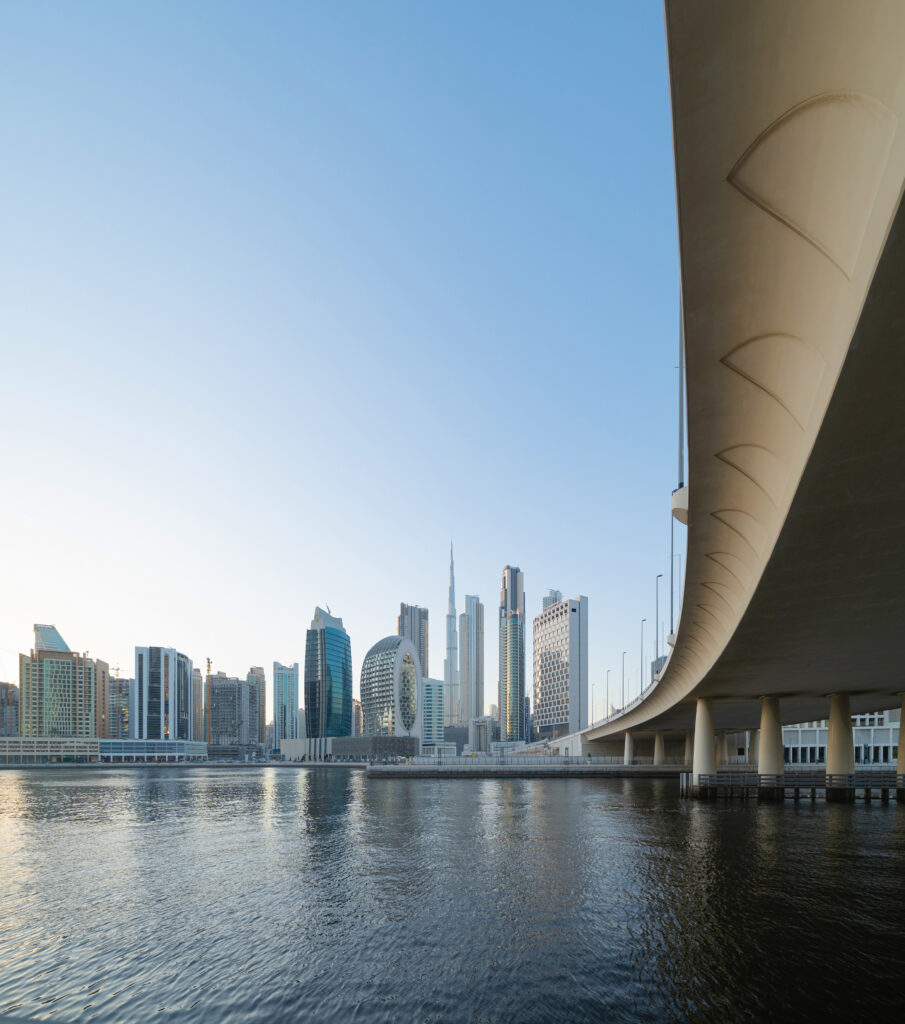 Burj Khalifa with lake or river and bridge in Dubai Downtown skyline, United Arab Emirates or UAE. Financial district and business area in urban city. Skyscraper buildings with blue sky. Reflection.